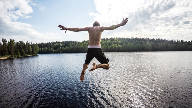 En person hoppar från hög höjd ner i vattnet. 